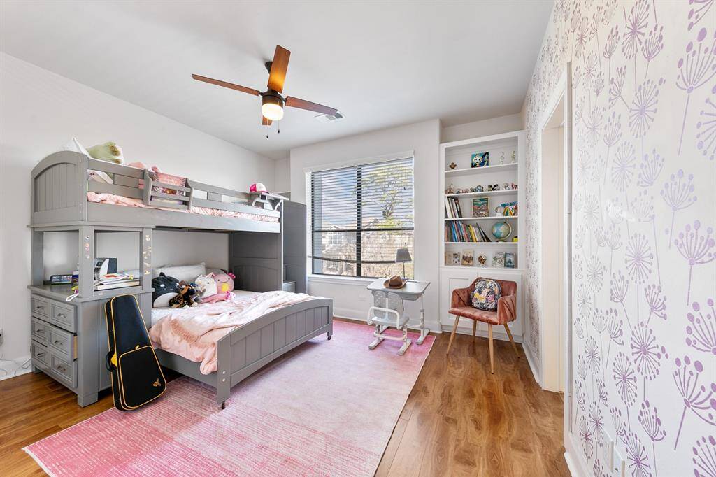 The second of two secondary bedrooms upstairs offers gorgeous treetop views over the front yard.  This bedroom offers engineered hardwood flooring, built-in cabinetry, a walk-in closet, and direct en-suite access to one of the two vanities in the Jack-and-Jill bath upstairs.