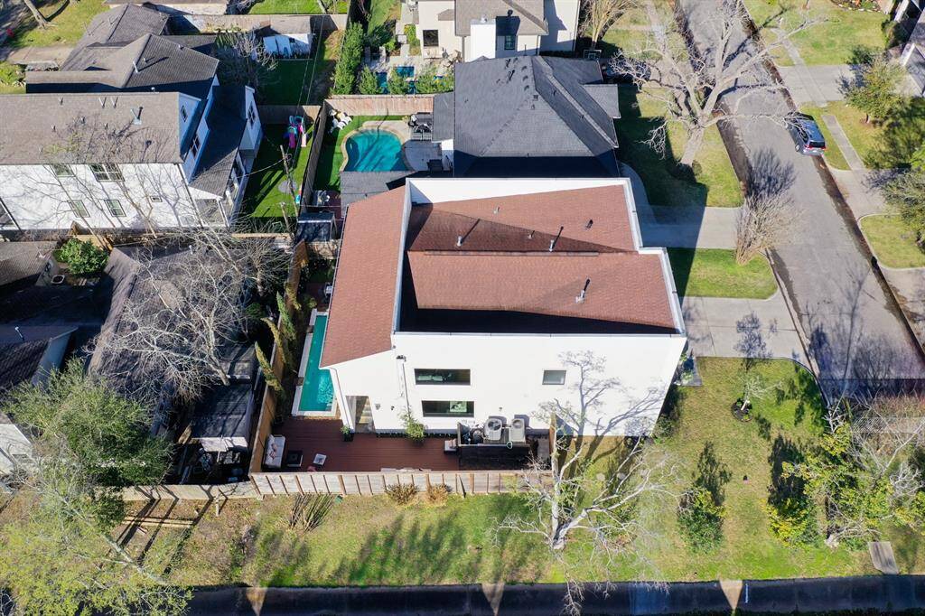 An aerial view of the home highlights its exceptional architectural design, seamlessly blending modern and traditional elements. The bonus features of this ideal contemporary family home shine even outside: the pool, the ample outdoor entertaining space, and the sunlit privacy of the outdoor areas surrounding this home bordering spacious easements.