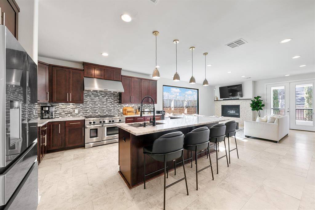 The gourmet kitchen opens seamlessly to the sun-drenched living room, allowing the chef to stay connected with the rest of the family during meal prep.  Walls of windows flood the space with natural light, framing stunning views while enhancing the bright and airy atmosphere.  Note the nostalgic view of the freight train in this photo - the trains passing on the other side of the gulley adjacent are barely audible due to the quiet-zone designation for inner-city train lines and a welcome sight.