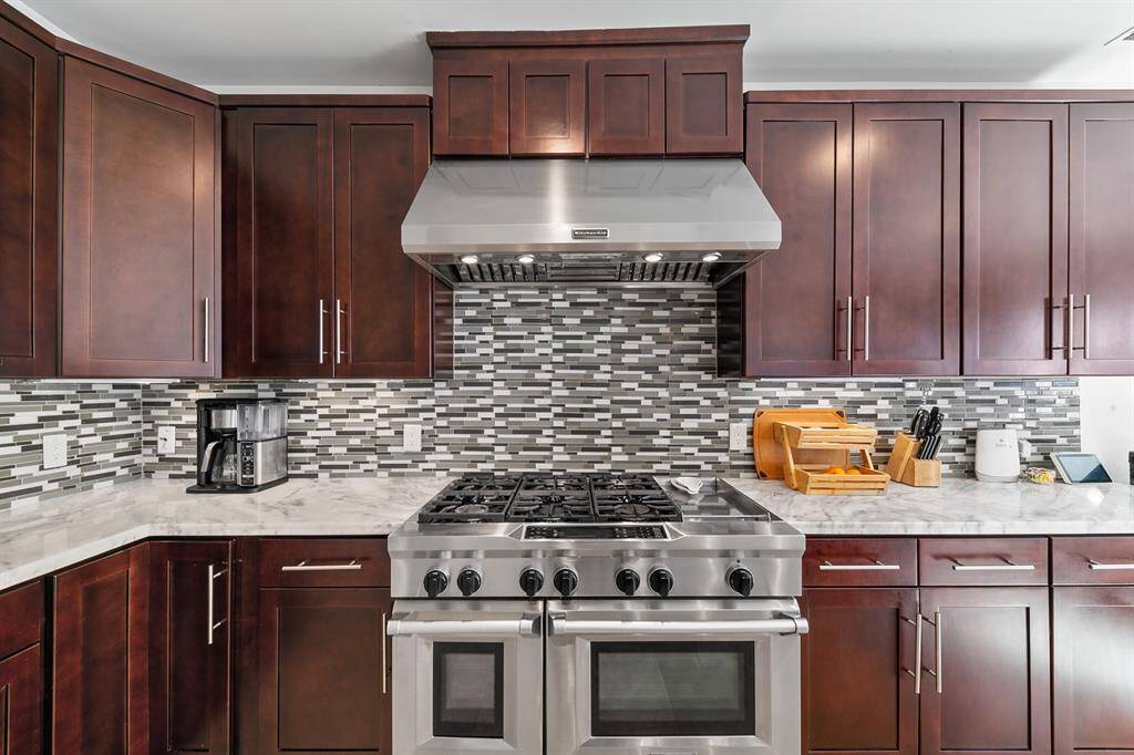 The Kitchen Aid gas range is a chef's dream with 6 burners, griddle, and double ovens.   An abundance of hardwood cabinetry provides ample storage space, ensuring the kitchen stays organized and clutter-free.