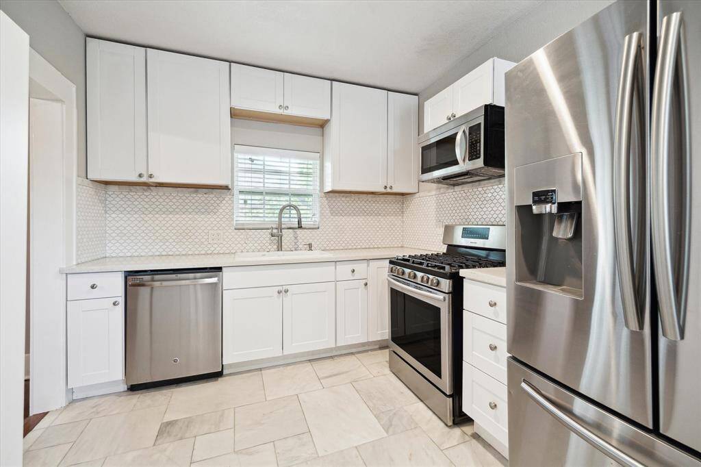 Renovated kitchen boasts quarts counters, stainless appliances, updated cabinets, and the must have window above the sink!