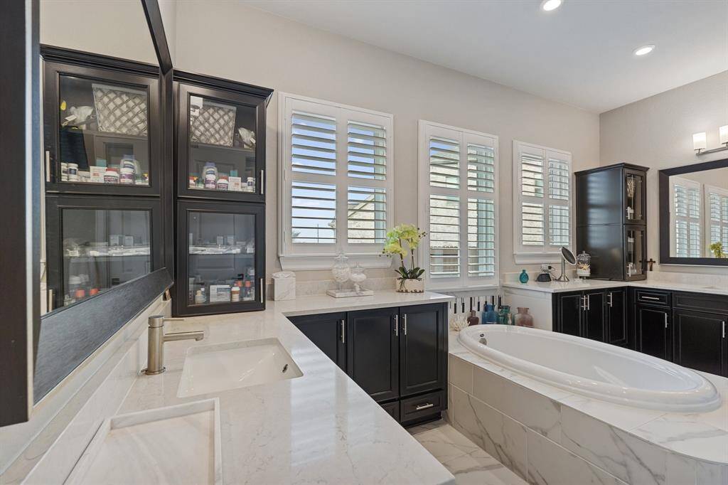 The luxurious primary bathroom features ample storage and counter space, double sinks, and a centrally positioned large bathtub, creating a perfect balance of functionality and relaxation.