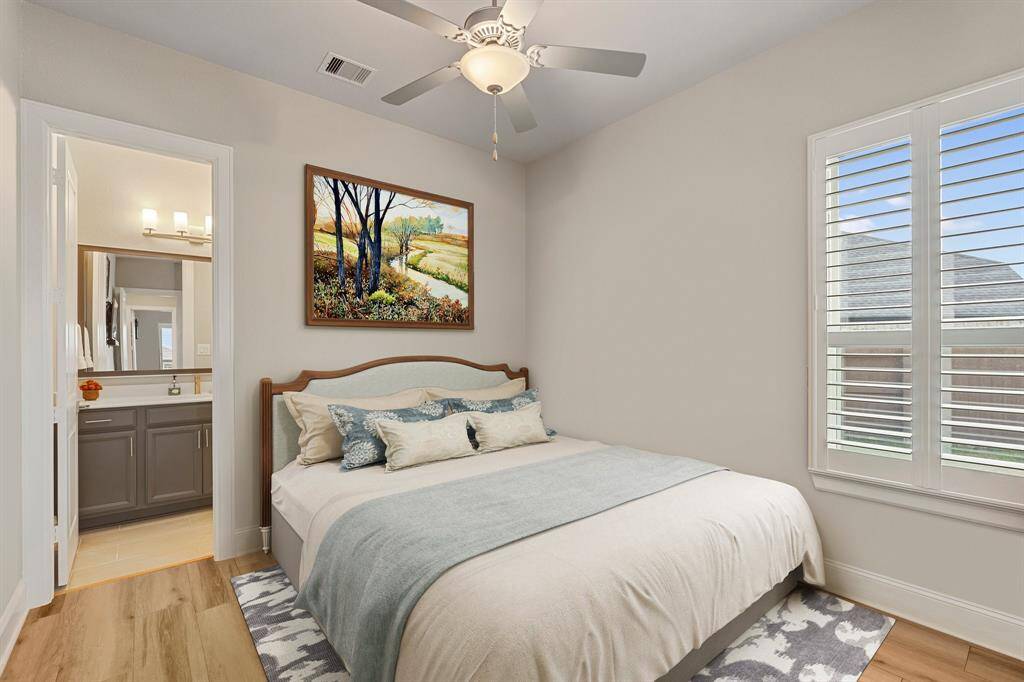 This spacious bedroom features sleek engineered wood flooring, a window with privacy blinds, a ceiling fan for comfort, and a private ensuite bathroom, offering both style and convenience. *Virtually Staged*