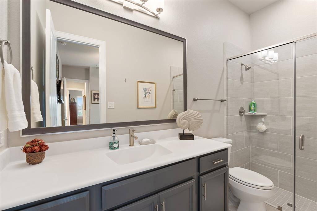 This stunning bathroom features an oversized sink vanity, a spacious tiled walk-in shower, and a modern toilet, creating a perfect blend of comfort and luxury.