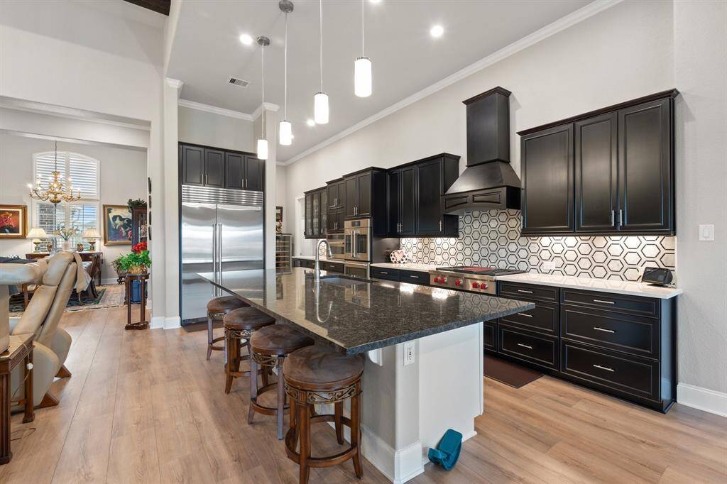 This stunning kitchen features modern black cabinets, sophisticated recessed lighting, and eye-catching pendant lights that perfectly highlight the expansive kitchen island, making it a dream space for cooking and entertaining!