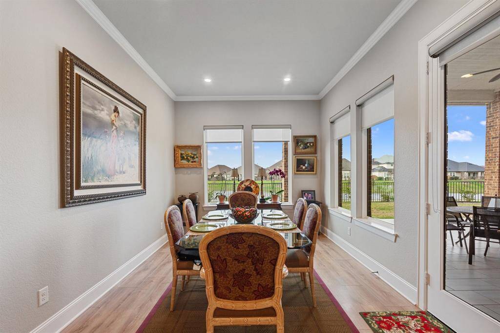 The inviting breakfast nook boasts multiple windows with privacy shades, elegant crown molding, and stunning engineered wood flooring, creating a bright and stylish space to start your day!