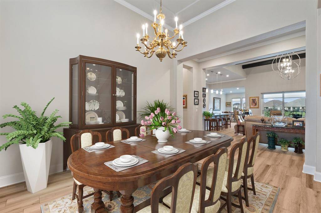The elegant dining room boasts soaring high ceilings, refined crown molding, and a stunning golden chandelier, creating the perfect ambiance for memorable gatherings! *Virtually Staged*