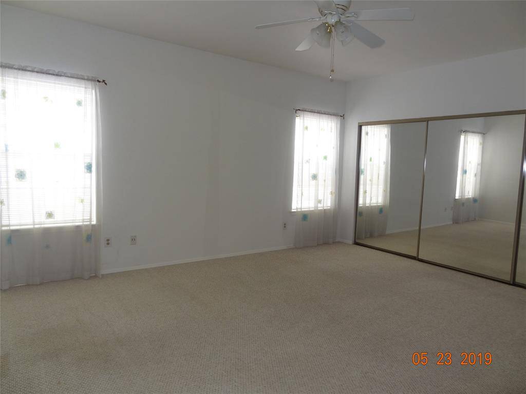 Bedroom 2 with mirrored sliding closet doors.  So much space in this room.  Features ceiling fan and blinds for windows.