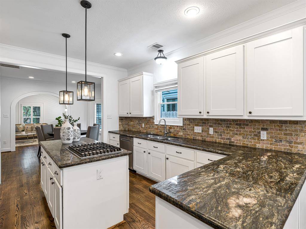 An oversized three-basin undermount sink makes meal prep and clean-up a breeze, while wood floors and crown molding seamlessly unify the space.