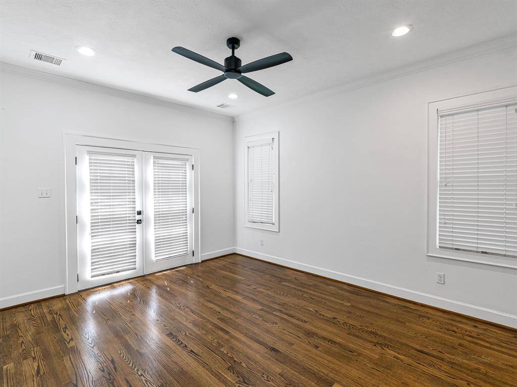 Welcome to your primary retreat! French doors open to the backyard deck, while bright windows and recessed lighting fill the room with natural light. Wood floors and crown molding enhance the space with charm and elegance.