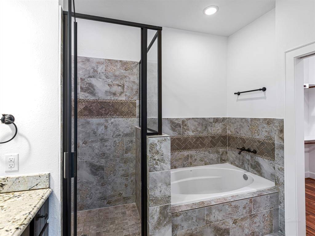 A large walk-in shower and a spa-like garden tub provide ultimate relaxation. Custom tiling surrounds both the tub and walk-in shower, enhancing the elegance of this serene retreat