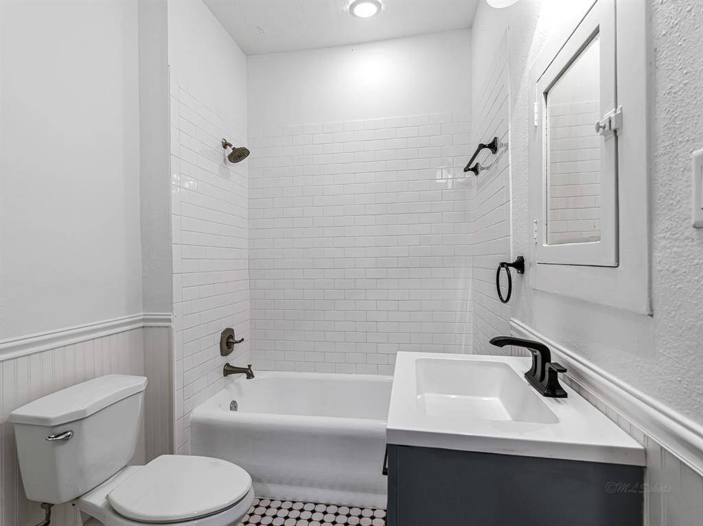 The secondary bathroom has been updated with stylish subway tile in the tub/shower combo, adding a fresh, modern touch. Wainscoting accents further enhance the room's charm and character.