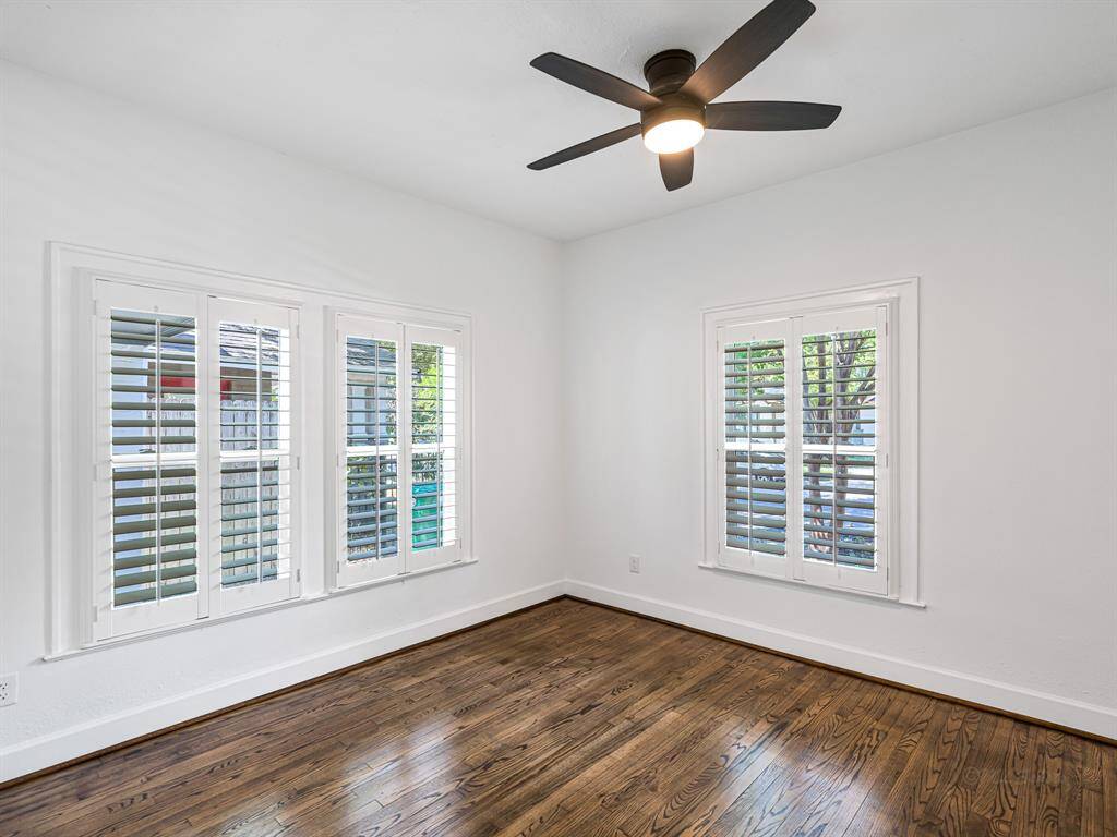 The third bedroom features wood floors, a spacious closet, and elegant plantation shutters. A ceiling fan ensures the room stays cool and comfortable.