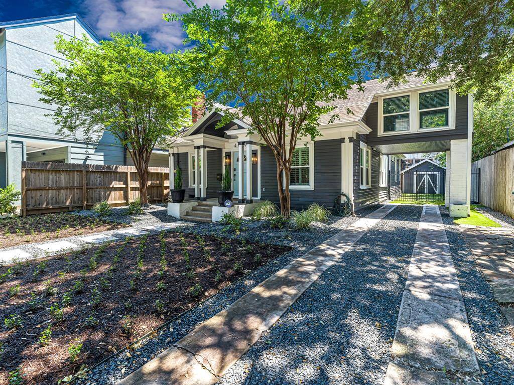 A long driveway with a charming porte co·chère offers ample parking for residents and guests alike. The yard has been professionally landscaped with asiatic jasmine and blackstar gravel for low maintenance ground cover. Note the wide pavers that lead to the front door.