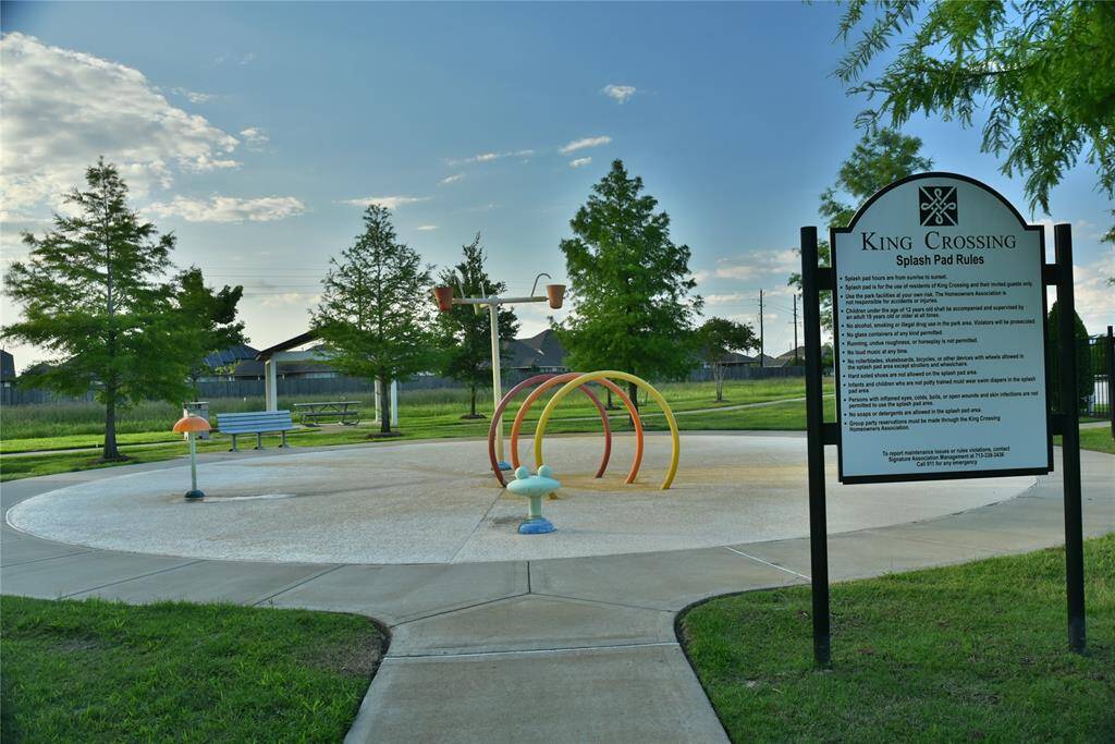 A well-maintained splash pad area in King Crossing, featuring playful water features, a seating area, and surrounding greenery. It's a family-friendly spot perfect for relaxation and outdoor fun.