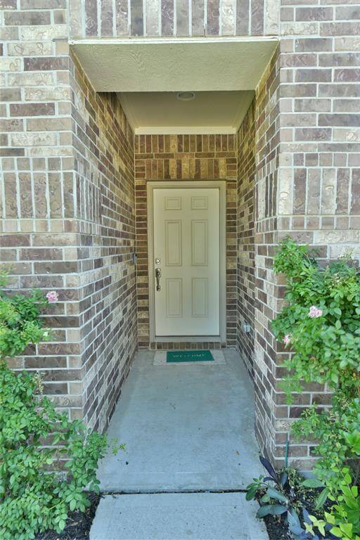 Inviting front entrance framed by elegant brickwork and lush greenery.