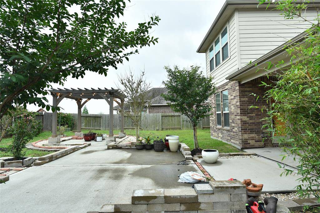 Charming backyard with a spacious patio, lush greenery, and a cozy pergola for relaxation.