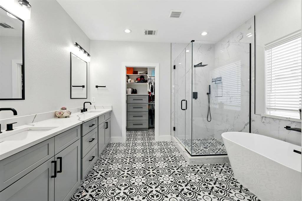 The primary restroom is a spa-like escape, boasting a free soaking tub, a separate glass-enclosed shower, and dual sinks with modern fixtures and finishes.