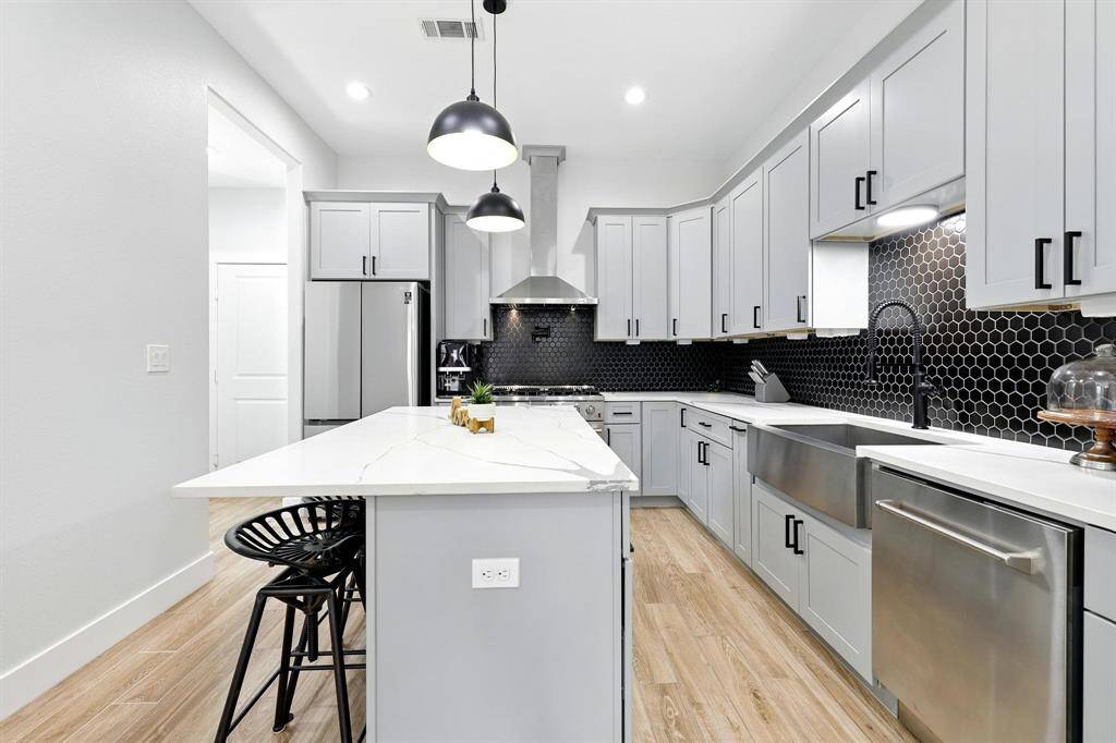 The kitchen just steps away, is equally striking-boasting a generous island with seating, quartz countertops, custom cabinetry, and state of the art appliances.