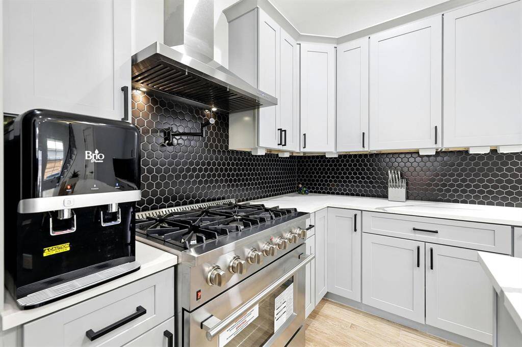 At the center of this sleek, modern kitchen is a professional-grade-6-burner gas range, ready to inspire the next home chef!