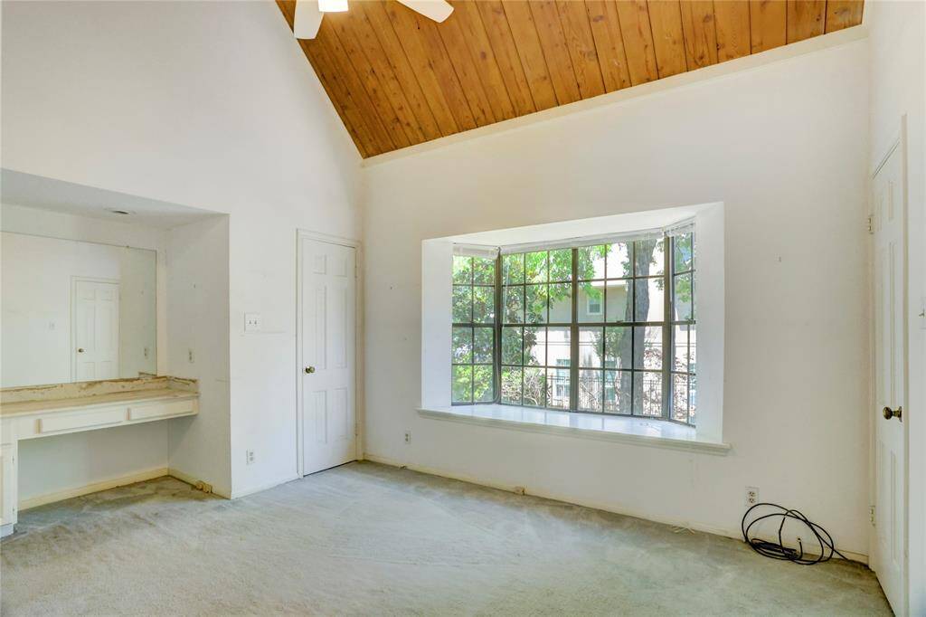 The 11x15 SF 2nd bedroom has a built in desk and vaulted ceiling with exposed wood.