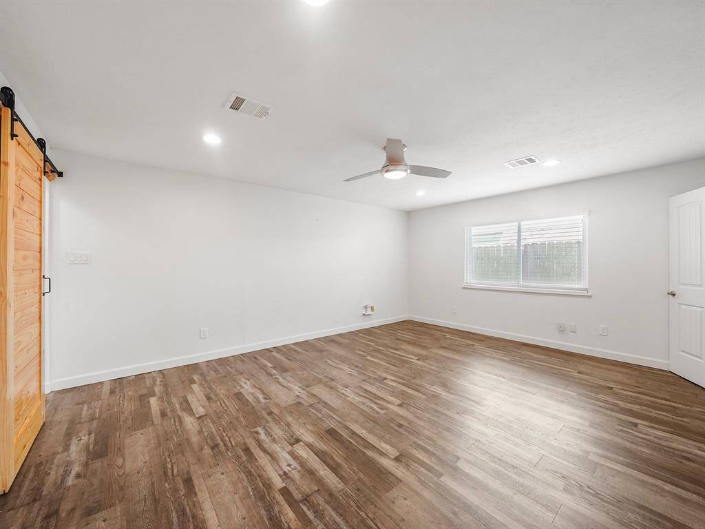 Primary bedroom with laminate floors and custom barnyard door.