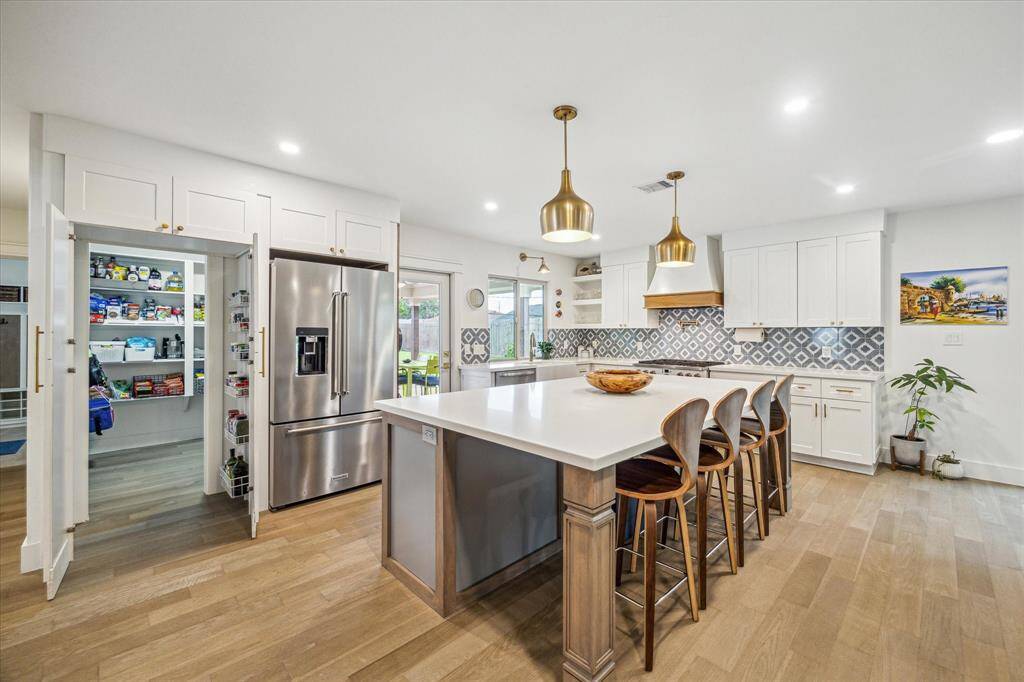 Bright kitchen with generous island, bar stools, and walk-in pantry.