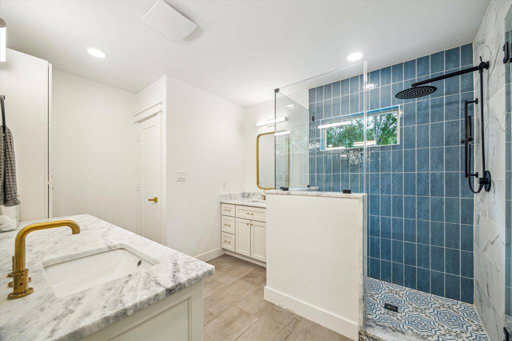 Well-lit primary bath with a sleek glass-enclosed shower.