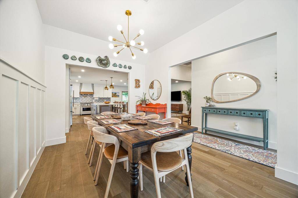 Bright and stylish dining area accented by wainscoting and a hanging chandelier.