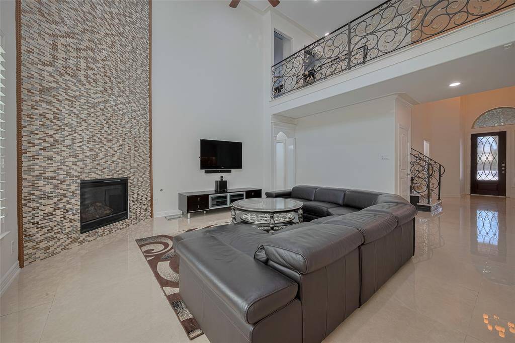 Expansive family room with soaring ceilings and a floor-to-ceiling tile gas fireplace, creating an impressive focal point.