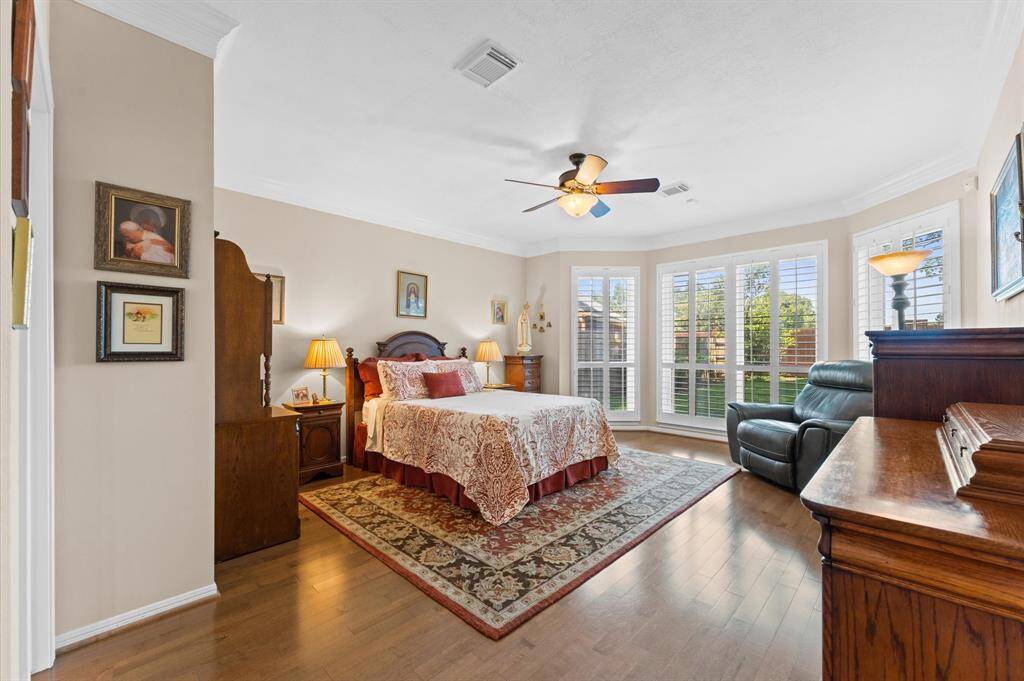 The primary bedroom has engineered wood floors and a bay window with plantation shutters. There is double crown molding too.