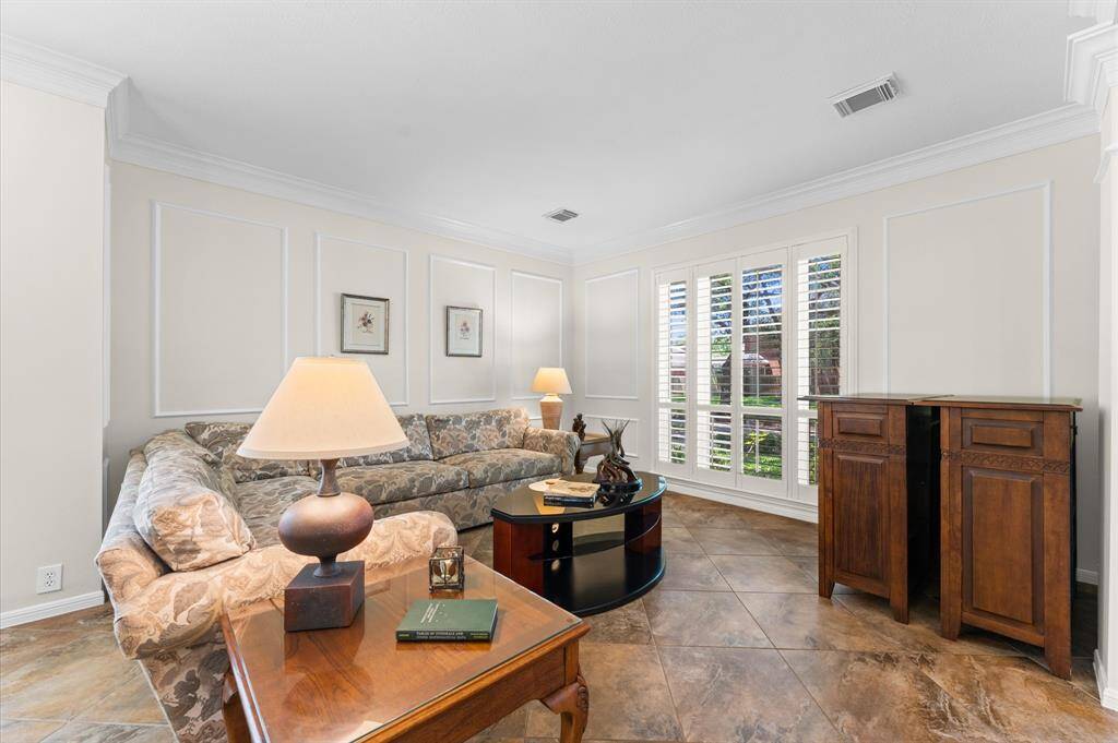 The formal living room has picture frame moldings on on walls. Note the Plantation shutters which are on most windows throughout house.