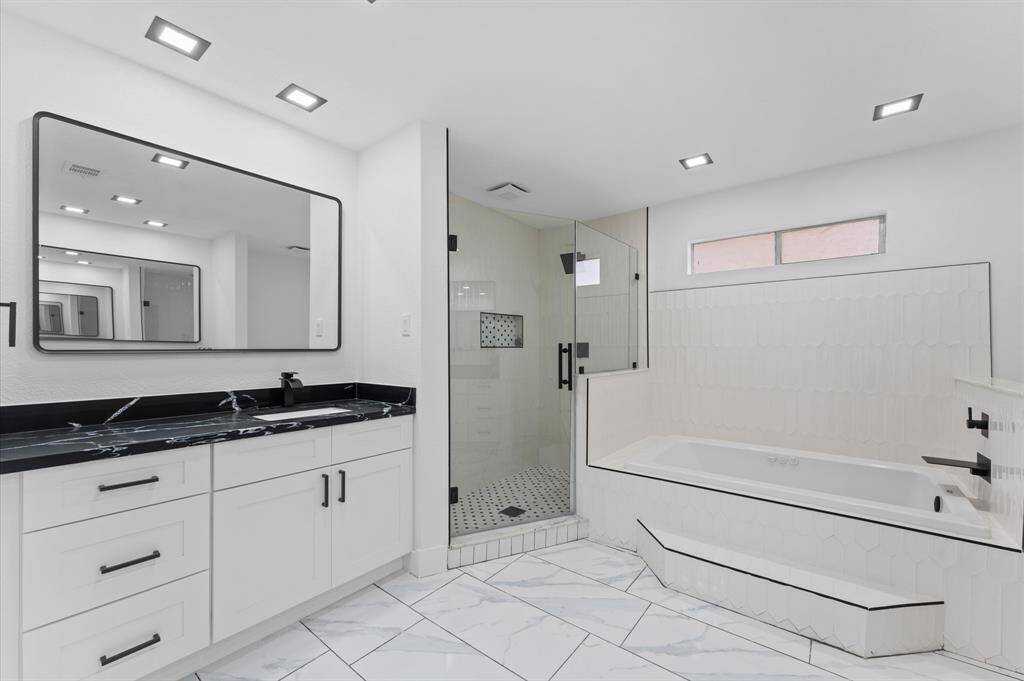 Luxurious en-suite bath with a double vanity, soaking tub, spacious walk-in shower, and dual closets.