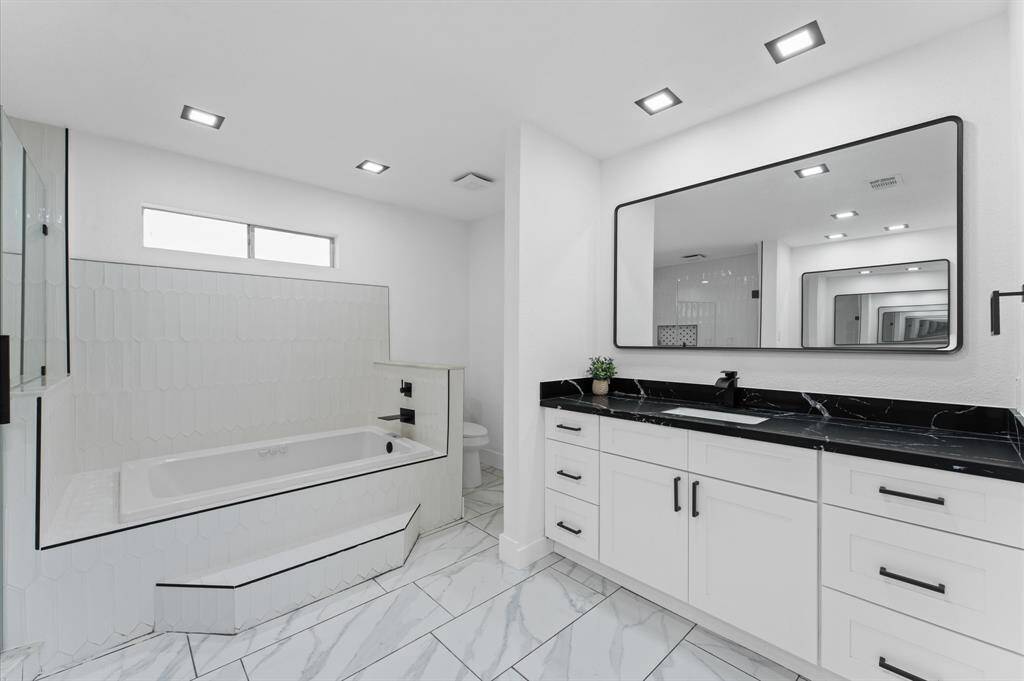 Luxurious en-suite bath with a double vanity, soaking tub, spacious walk-in shower, and dual closets.