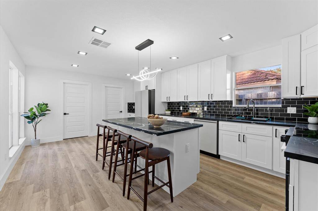 Gorgeous modern kitchen with an oversized island, sleek finishes, ample cabinet space, and a large pantry for storage.