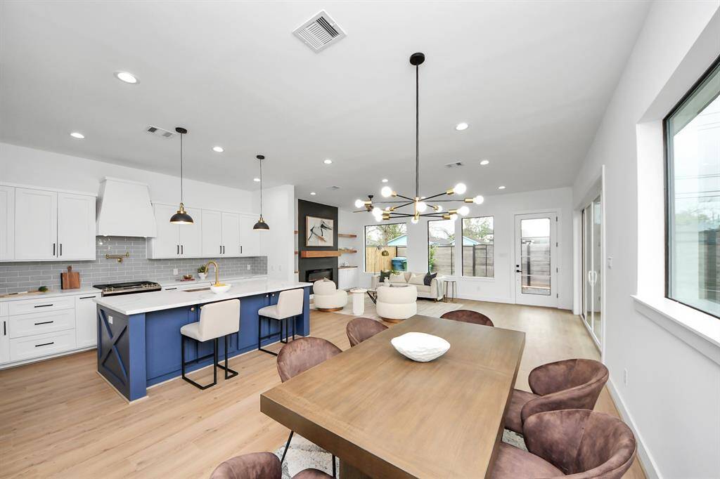 This dining room is bathed in naturallight streaming through expansivewindows and features a modern chandelier.