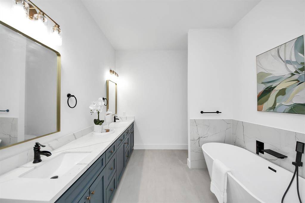The primary bathroom features dual sinks, light countertops, freestanding tub, and separate shower.