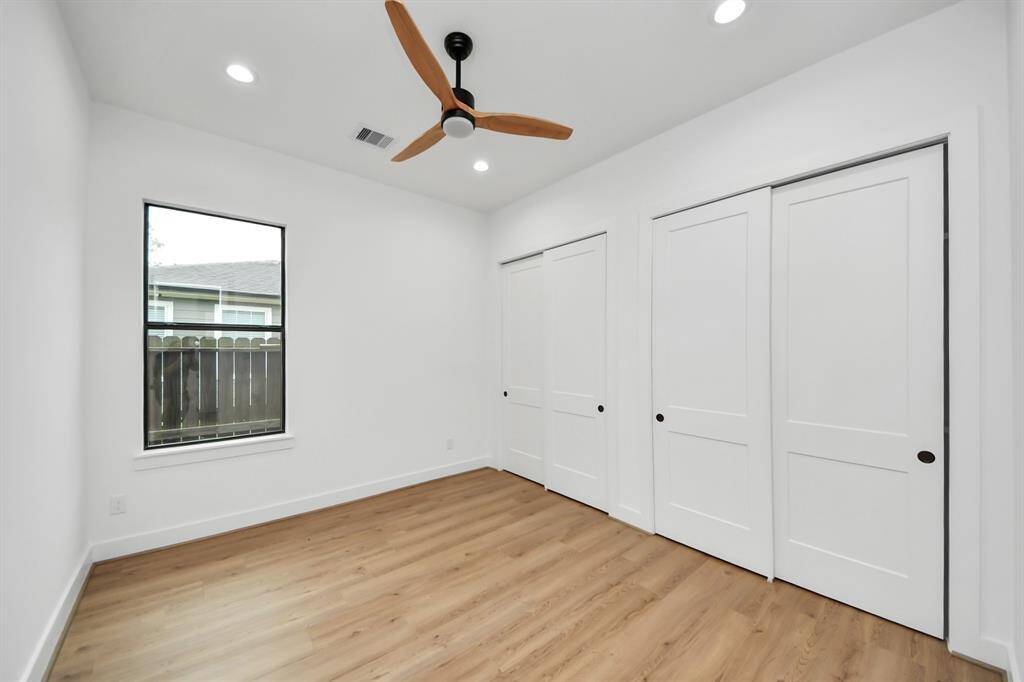Secondary bedroom features awindow, ceiling fan, and recessed lighting.