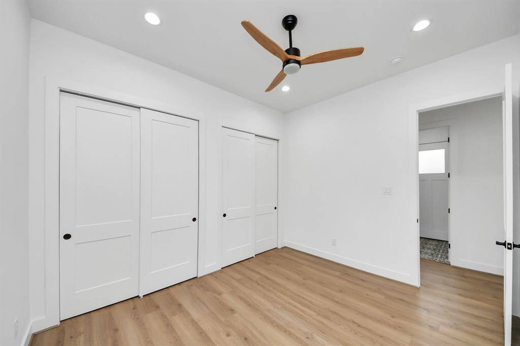 Secondary bedroom features awindow, ceiling fan, and recessed lighting.