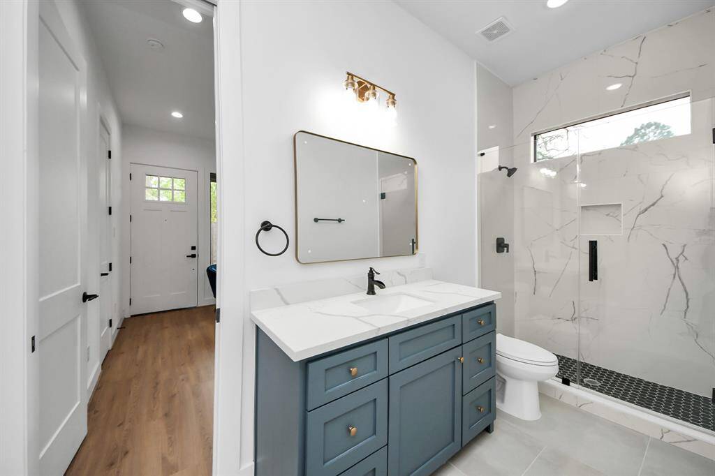 Secondary bathroom features a walk-in shower with tile surround and spacious vanity.