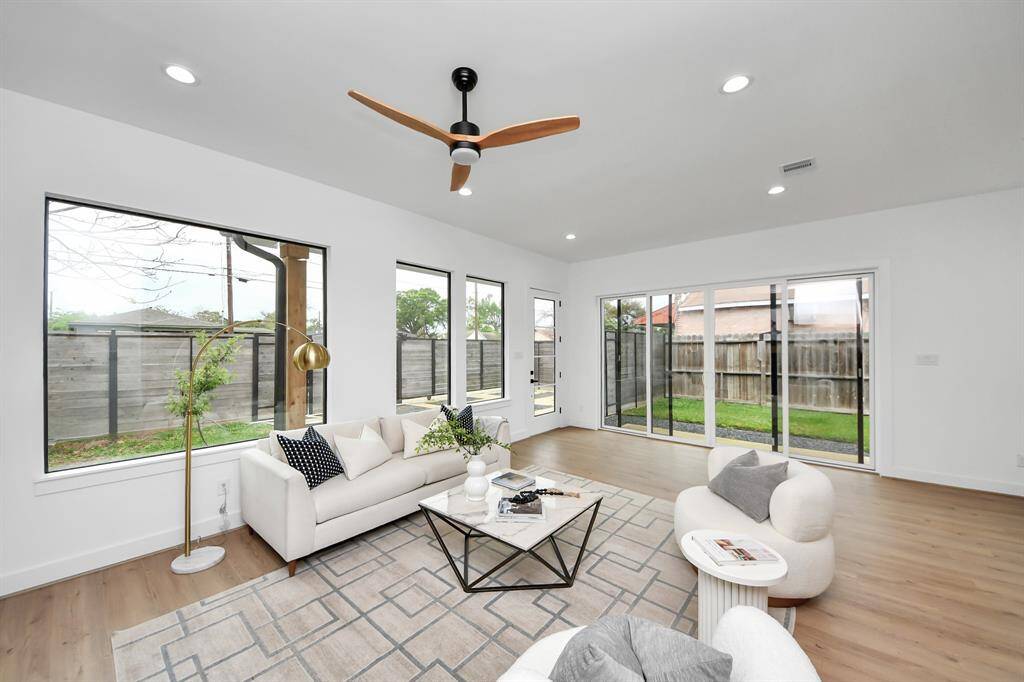 The living room has large windows, ceiling fan, recessed lighting, and sliding glass doors leading to the backyard.