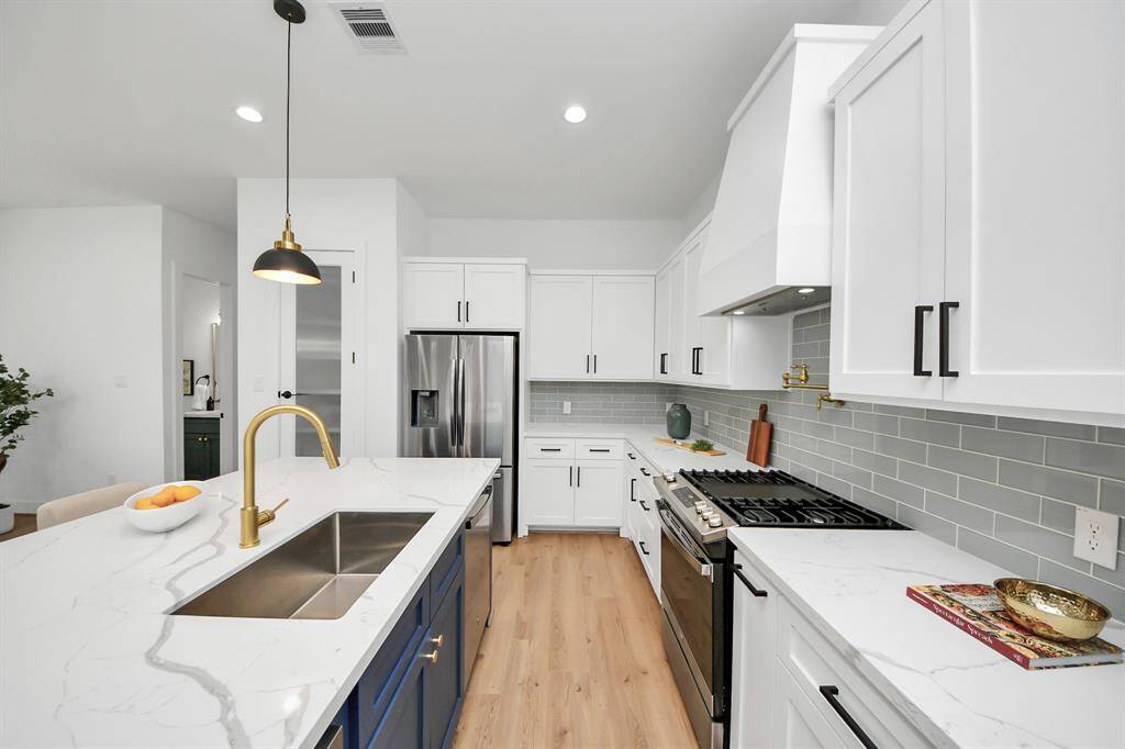 The kitchen features a pot filler, sleek quartz counters, recessed lighting, and tile backsplash.