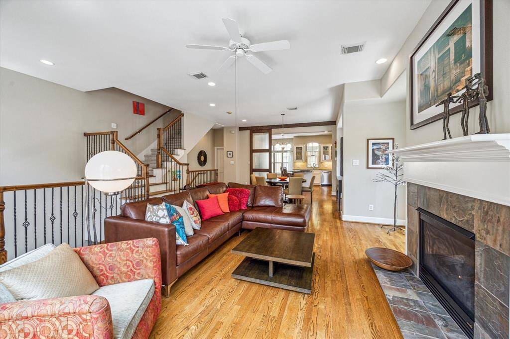 A wide-open layout connects the living room, dining area, and kitchen, with rich hardwood floors, elegant ceiling detail, and views that stretch from the front balcony to the rear of the home, creating an easy flow for entertaining or everyday living.