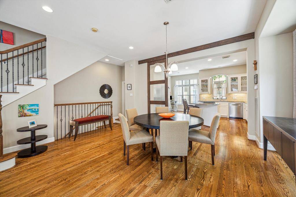 A warm and open dining area connects seamlessly with the kitchen, framed by rustic wood beams and softly lit by modern fixtures, creating a comfortable space to gather with family and friends.