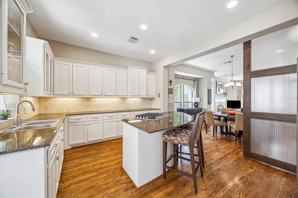 An abundance of cabinetry, granite countertops, and under-cabinet lighting offer both style and function in this well-appointed kitchen that flows seamlessly into the open-concept living and dining areas.