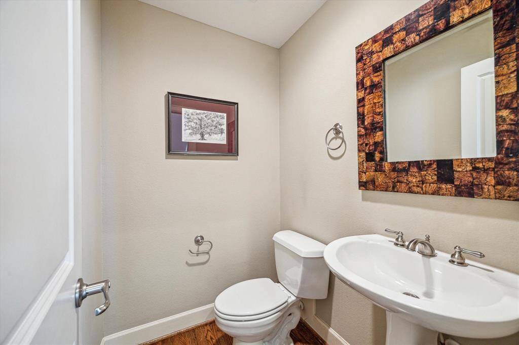 A conveniently located powder bath on the main level features a pedestal sink and neutral finishes, ideal for guests.