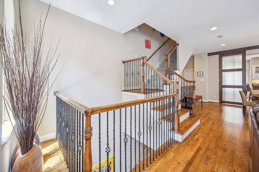 Warm wood floors and wrought-iron railings enhance the architectural detail of this central stairwell, which connects all three levels of the home with style and ease.
