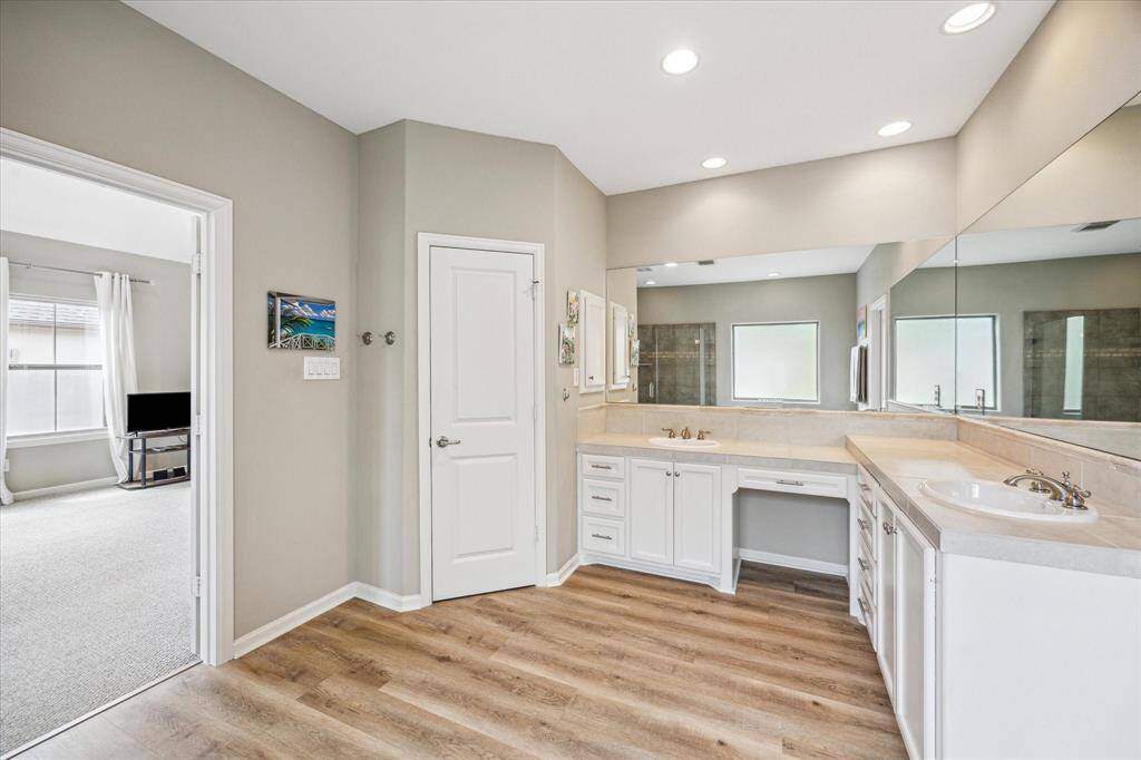 Double vanity layout offers ample counter space, under-sink storage, and a built-in makeup station. Wall-to-wall mirror enhances brightness and adds a sense of openness.
