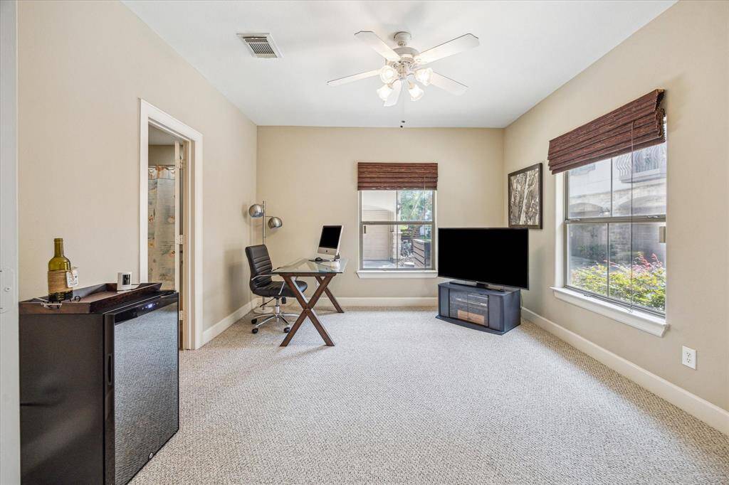 Large windows allow natural light to brighten this versatile first-floor space, ideal as a home office, guest suite, or private lounge. Neutral tones and plush carpeting create a comfortable atmosphere, while the ensuite bath and convenient beverage fridge add functionality.