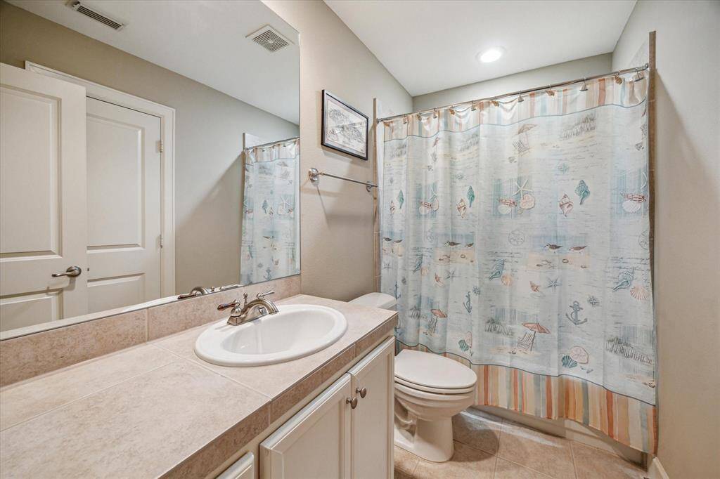 The first-floor bathroom features a full tub/shower combo, generous countertop space, and neutral tilework that blends seamlessly with the home’s overall aesthetic.